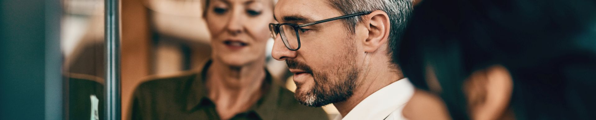 Putting their heads together to perfect the plan. Shot of a group of businesspeople having a brainstorming session on a glass wall in a modern office.